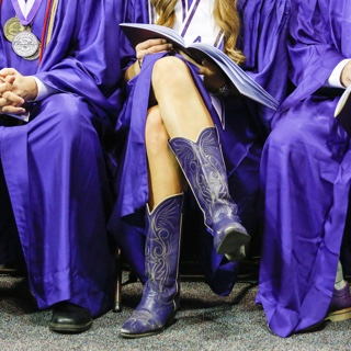 A Ӱɴý graduate wears purple cowboy boots with her commencement gown