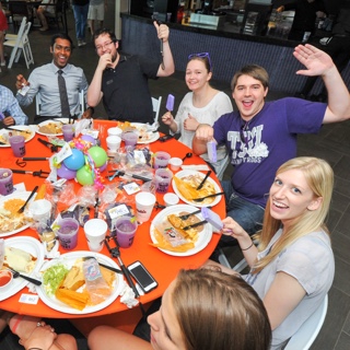 A group of Ӱɴý students raise their celebratory purple margaritas at a festive round table