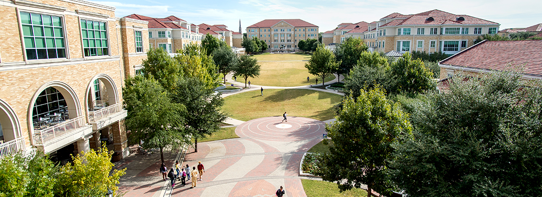 High up view of the Ӱɴý campus commons with scattered groups of pedestrians. Frog Fountain is visible in the distance and a huge horned frog logo can be seen on the brick walkway