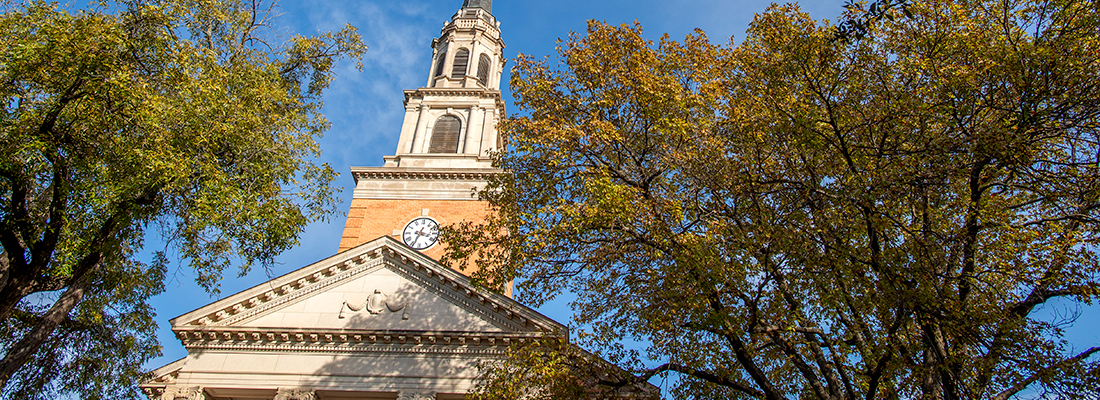 The steeple of the Robert Carr Chapel on the Ӱɴý campus, framed by trees and a blue sky.