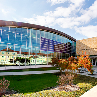 An exterior of the Ӱɴý Campus Rec center; other campus buildings are reflected in its shiny surface.